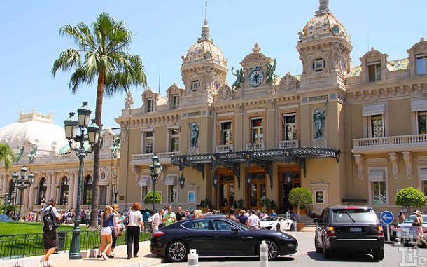 Tourists ogle the wealthy noted for their very expensive cars out front