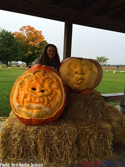 Terri stands with her giant sculpted pumpkins, the big one is 380Lbs.