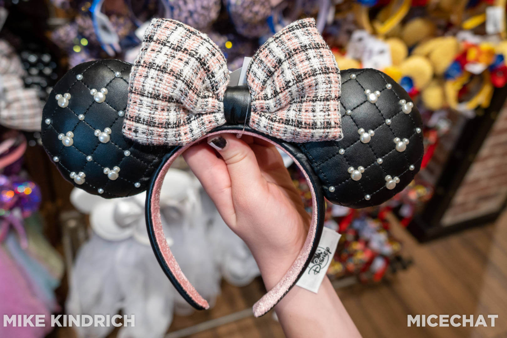 A Minnie Ear Headband, decorated with Hidden Mickeys made of pearls against faux leather ears and a tweed bow