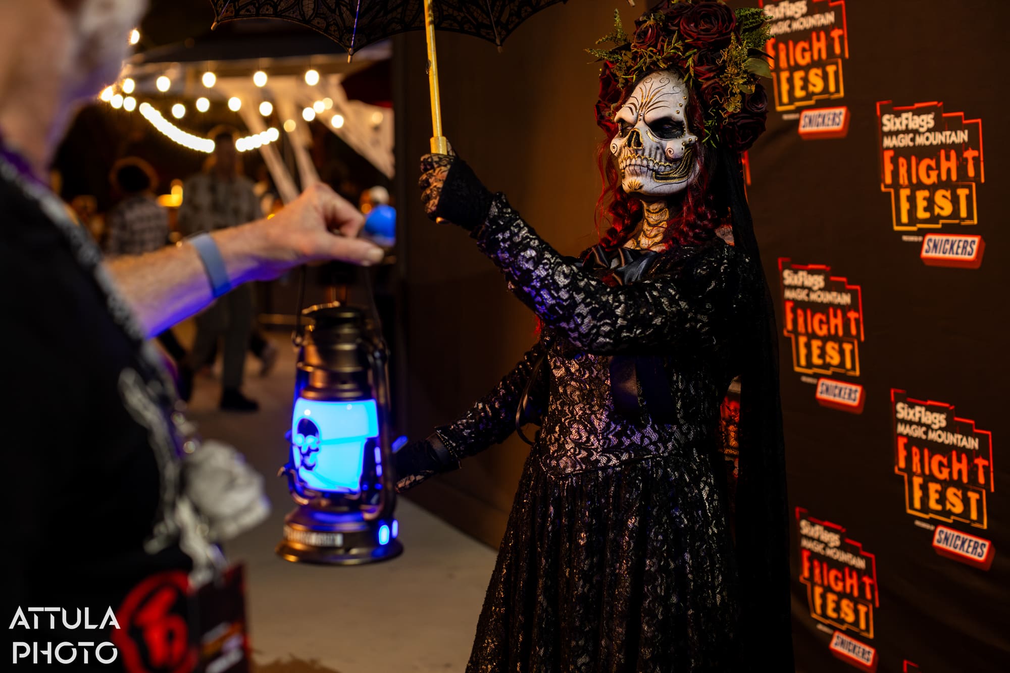 Scare actor changing an interactive lantern's color in Plaza de la Muerte at Six Flags Magic Mountain Fright Fest