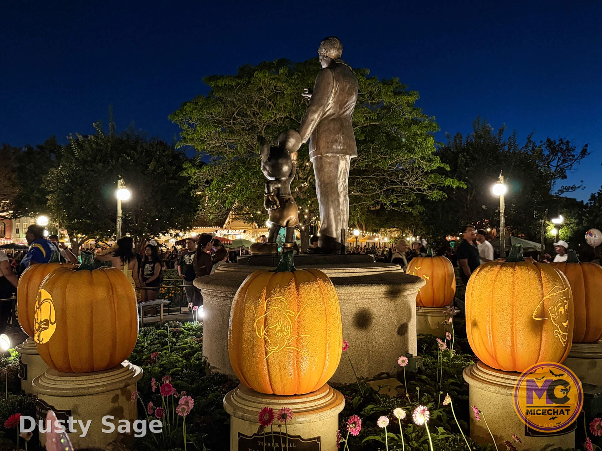 The Partners statue surrounded by pumpkins at night in Disneyland's hub